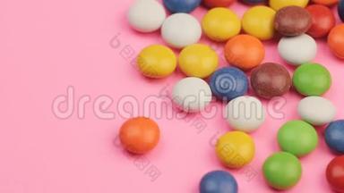 在粉红背景下，合上一堆五颜六色的巧克力糖果。